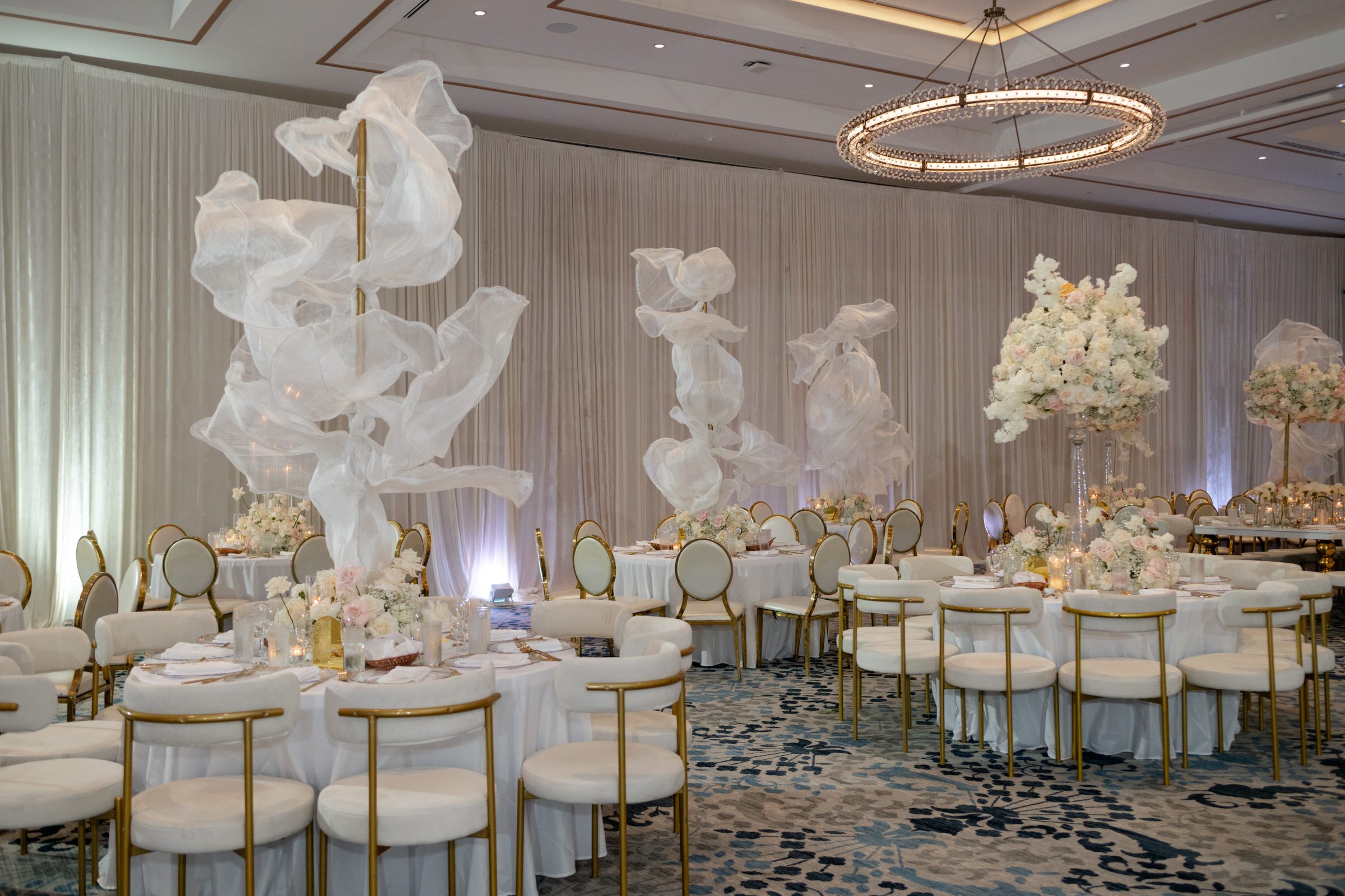 Floating white fabric installations above wedding reception tables